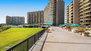 Un ensemble immobilier résidentiel comprenant plusieurs immeubles à étages, une cour centrale aménagée avec des espaces pour s’asseoir et de la verdure, ainsi qu’une pelouse bien entretenue.