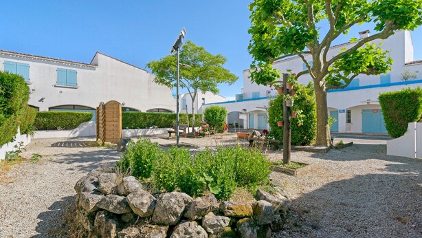 A courtyard with a stone wall, a bench, and a tree. - Studio on La Corniche with Shared Pool, Private Terrace, and Shared Garden (Saint-Palais-sur-Mer)