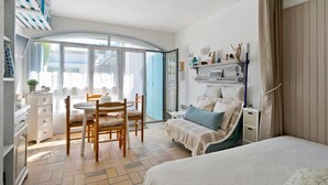 A bedroom with a bed, a chair, a table, and a wardrobe. - Studio on La Corniche with Shared Pool, Private Terrace, and Shared Garden (Saint-Palais-sur-Mer)