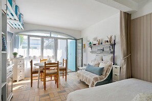A bedroom with a bed, a chair, a table, and a wardrobe. - Studio on La Corniche with Shared Pool, Private Terrace, and Shared Garden (Saint-Palais-sur-Mer)