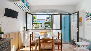 A dining area with a round table, chairs, and a view through an open door to the outside. - Studio on La Corniche with Shared Pool, Private Terrace, and Shared Garden (Saint-Palais-sur-Mer)