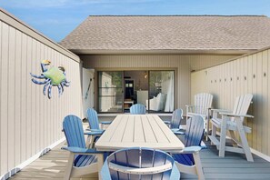 An outdoor deck with a wooden table and chairs, a large crab decoration on the wall, and a covered entrance. - Sea Colony West condo with lovely deck, pools, hot tubs, tennis, & beach shuttle (Bethany Beach)