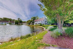 A lakeside view with a house, a grassy area, and a tree. - Sea Colony - 1021 West Pine Ct | Condo in Bethany Beach with 12 pools, hot tub (Bethany Beach)