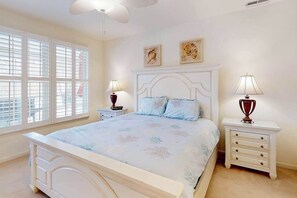 A bedroom with a bed, two bedside tables, a window, and wall art.