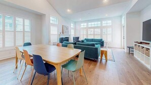 A spacious living area with a dining table, chairs, a sofa, and a TV.