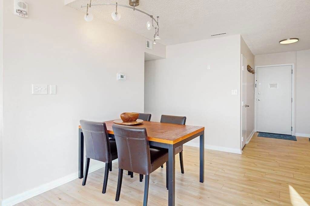 Een eetruimte met een houten tafel en stoelen, een plafondlamp en een deur op de achtergrond.