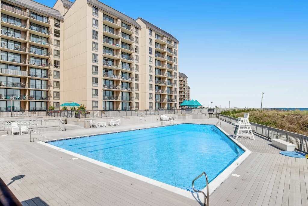 Une piscine dotée d’une plage, entourée d’un immeuble à plusieurs étages avec des balcons.