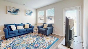 A living room with a blue sofa, a patterned rug, and a television. - Newly remodeled - dog friendly townhome with pools, tennis, washer/dryer & AC (Millville)