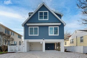 Ein zweistöckiges Haus mit Garage, weißem Zaun und Kiesweg.