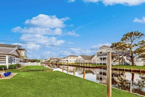 A residential area with houses along a canal, a clear sky, and a wooden fence. - Town of South Bethany waterfront home with boat ramp - 5-min walk to beach (Bethany Beach)