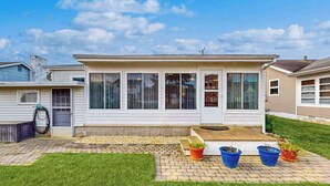 Una casa a un piano con un portico, un garage e un piccolo giardino sul retro con piante in vaso.