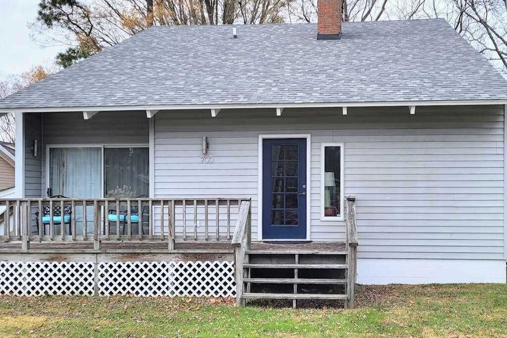 Einbungalow mit Veranda, einer blauen Tür und einem kleinen Vorgarten.