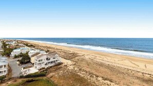Zona residencial costera con casas cerca de la playa, cielo despejado y el océano.