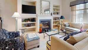 Ein Wohnzimmer mit Kamin, Sofa, Couchtisch und Fernseher.