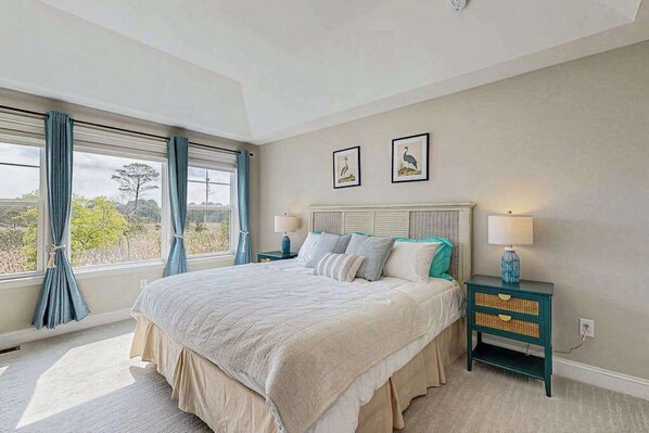 A bedroom with a large bed, a nightstand, a window with curtains, and two wall-mounted pictures. - Marlin Chase home with resort amenities, deck, grill, Free WIFI (Ocean View)
