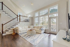 A spacious living room with a staircase, a large window, and a white sofa. - Marlin Chase home with resort amenities, deck, grill, Free WIFI (Ocean View)
