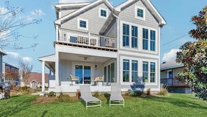 A two-story house with a balcony, a covered porch, and a well-maintained lawn. - Spacious pet friendly waterfront house w/deck, patio, balcony & gas grill (Bethany Beach)