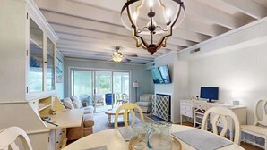 A modern living room with a dining area, a television, and a ceiling fan. - Mallard Lakes townhouse in peaceful community with pool, hot tub, fishing pier (Selbyville)