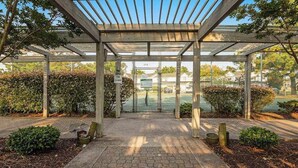 A covered outdoor area with a paved walkway, wooden posts, and a metal fence. - Mallard Lakes townhouse in peaceful community with pool, hot tub, fishing pier (Selbyville)