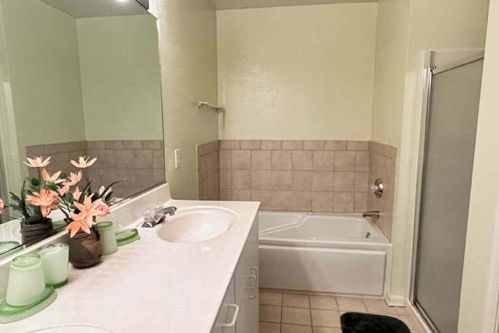 Een badkamer met twee wastafels, een badkuip en een douche.