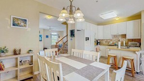 Un espace repas avec une table, des chaises et une cuisine en arrière-plan.