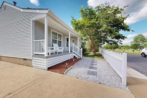 A single-story house with a porch, a small garden area, and a white fence. - Peaceful single family home with shared pool and sports courts access (Frankford)