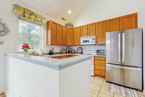A kitchen with wooden cabinets, a stainless steel refrigerator, a microwave, and a sink. - Bear Trap Dunes townhouse w/shared pool, tennis, fitness center, on-site golf (Ocean View)