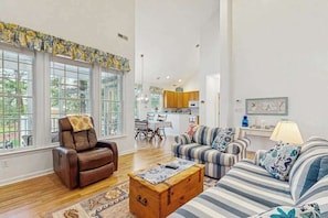 A spacious living room with a leather chair, striped sofa, and a wooden chest of drawers. - Bear Trap Dunes townhouse w/shared pool, tennis, fitness center, on-site golf (Ocean View)