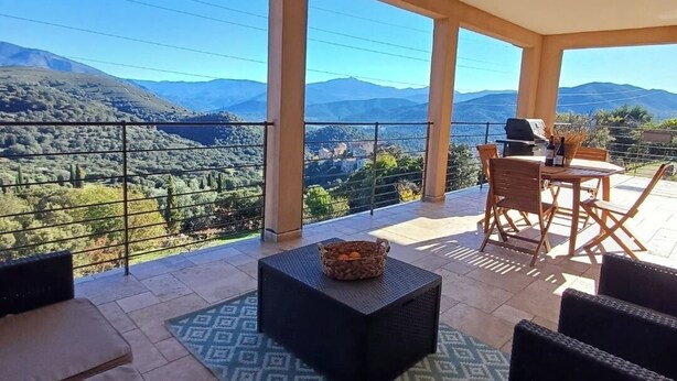 A balcony with a view of mountains, a table with chairs, and a basket of fruit. - Top of villa Panoramic view with private pool (Moltifao)