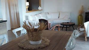 A dining area with a wooden table, white chairs, a woven centerpiece, and a sofa in the background. - Top of villa Panoramic view with private pool (Moltifao)