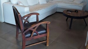 A living room with a sectional sofa, a wooden chair, a round coffee table, and a large mirror. - Top of villa Panoramic view with private pool (Moltifao)