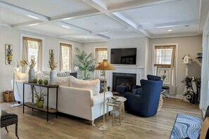 A living room with a sofa, armchairs, a TV, and a fireplace. - Town of Bethany Beach house w/private pool, hot tub, games, deck, grill (Bethany Beach)