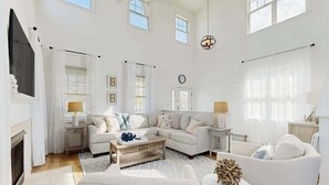 A spacious living room with a fireplace, a large sectional sofa, a coffee table, and a round side table with decorative items. - Bayside Resort house w/community pools, hot tubs, tennis courts & on-site golf (Selbyville)