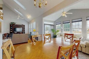 A spacious living area with a dining table, chairs, sofas, a TV, and ceiling fans. - South Hampton house with shared community pool & tennis courts (Ocean View)