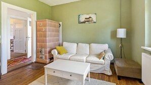 Una sala de estar con un sofá blanco, una mesita pequeña, una lámpara y un cuadro en la pared.