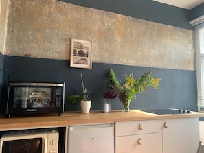 Eine Küche mit Mikrowelle, Geschirrspüler, einer Holzausziehtafel, einer Vase mit Blumen und einem gerahmten Bild an der Wand.