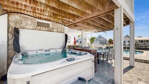 A hot tub under a wooden pergola with stone walls, a pool, and outdoor furniture. - Keen-Wik on the Bay bay front home w/private pool & hot tub (Selbyville)