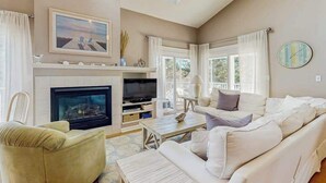 A living room with a fireplace, television, sofa, and a painting on the wall.