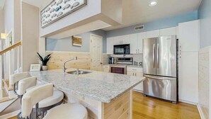 A modern kitchen with a granite countertop, stainless steel appliances, and a wooden floor.