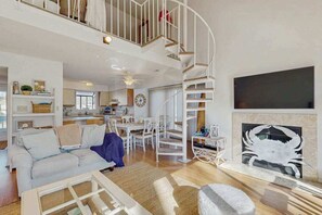 Ein geräumiger Wohnbereich mit weißem Wendeltreppe, einem Essbereich und einem Kamin mit Muscheldekor.
