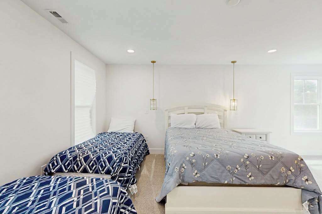 A bedroom with two beds, a white headboard, and a nightstand.