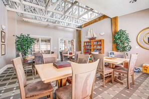 Ein geräumiges Zimmer mit hohen Decken, großen Fenstern und einem Bücherregal aus Holz.