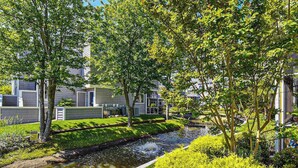 Un quartier résidentiel agrémenté d’un petit élément décoratif aquatique, de verdure et de bâtiments modernes.