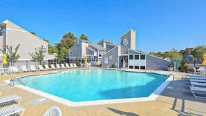 Une piscine avec des chaises longues, un espace abrité et un bâtiment doté d’un clocher.