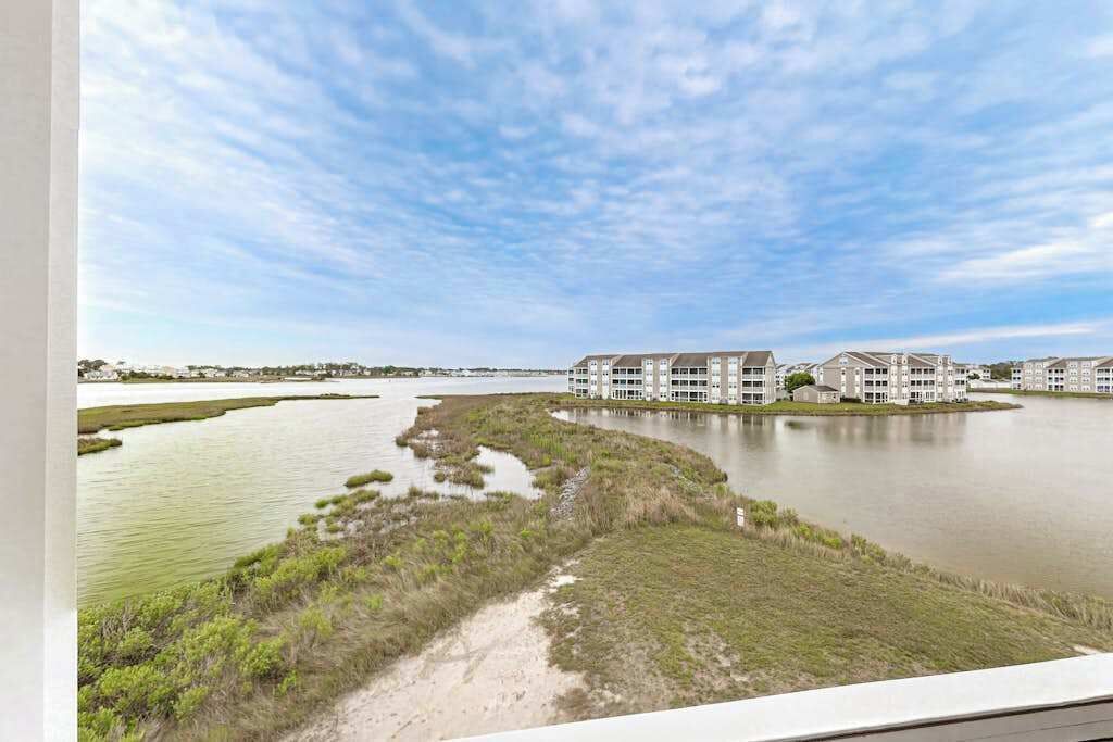 Een hotel aan het water met meerdere gebouwen, een rivier en grasvelden.