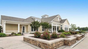 Une maison à deux étages avec un garage, une véranda et un jardin aménagé avec des arbustes et un bac à fleurs en pierre.
