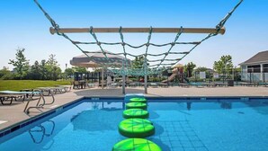 Une piscine avec des marches flottantes, un filet en corde et des sièges extérieurs.
