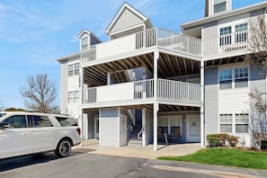A multi-story building with balconies, a garage, and a parked car. - Bethany Bay condo w/community pool, hot tub, tennis, on-site golf (Ocean View)