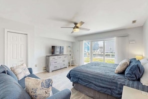 Ein Schlafzimmer mit Bett, einer Couch, einem Fernseher und einem Balkon mit Blick.