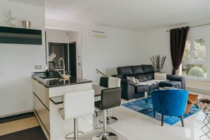 A modern living room with a sofa, a dining area with a bar, and a large window with curtains. - WELCS HOUSE 335 EMP with jacuzzi and terrace (Rosas / Roses)